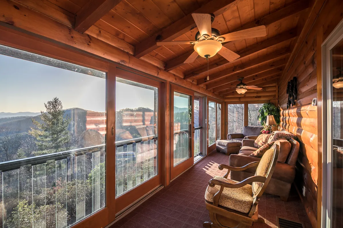 An inviting interior lounge with comfortable seating, wooden beams, and expansive floor-to-ceiling windows framing dramatic mountain views. The warm space is filled with natural light, ideal for both work and relaxation while remaining visually connected to the outdoors.
