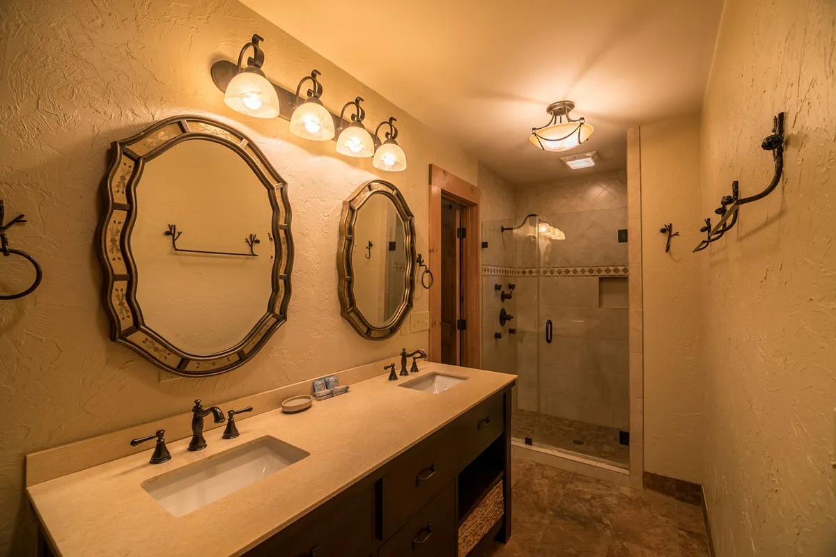An elegant bathroom featuring a double vanity with ornate mirrors and a spacious shower area. The space exudes a spa-like ambiance, perfect for personal grooming and relaxation.
